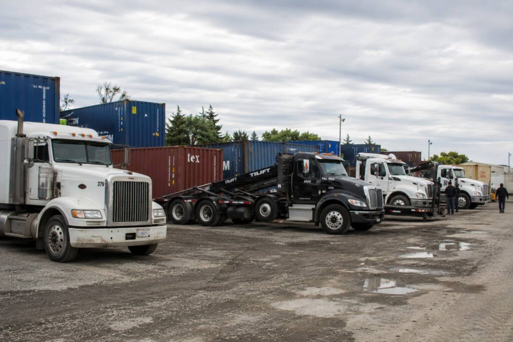 Fleet of delivery trucks loaded with shipping containers at a logistics depot